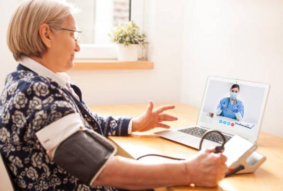 Lady taking blood pressure reading while on video call with clinician