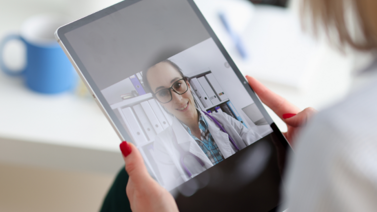 Patient holding iPad showing video consultation with healthcare professional