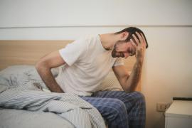 Man sitting on bed in pain